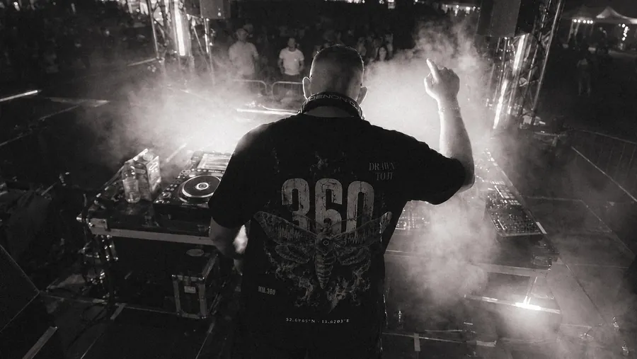DJ im MM.360-Shirt von hinten, umgeben von Licht und Haze