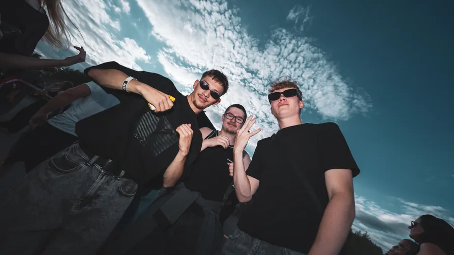 Drei Freunde aus tiefer Perspektive vor dem Abendhimmel
