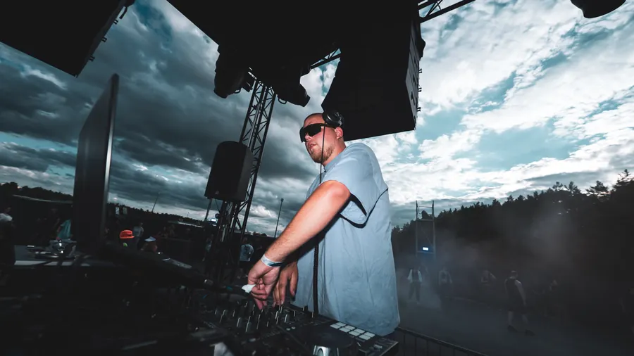 DJ mit Sonnenbrille am Mischpult unter dem offenen Abendhimmel
