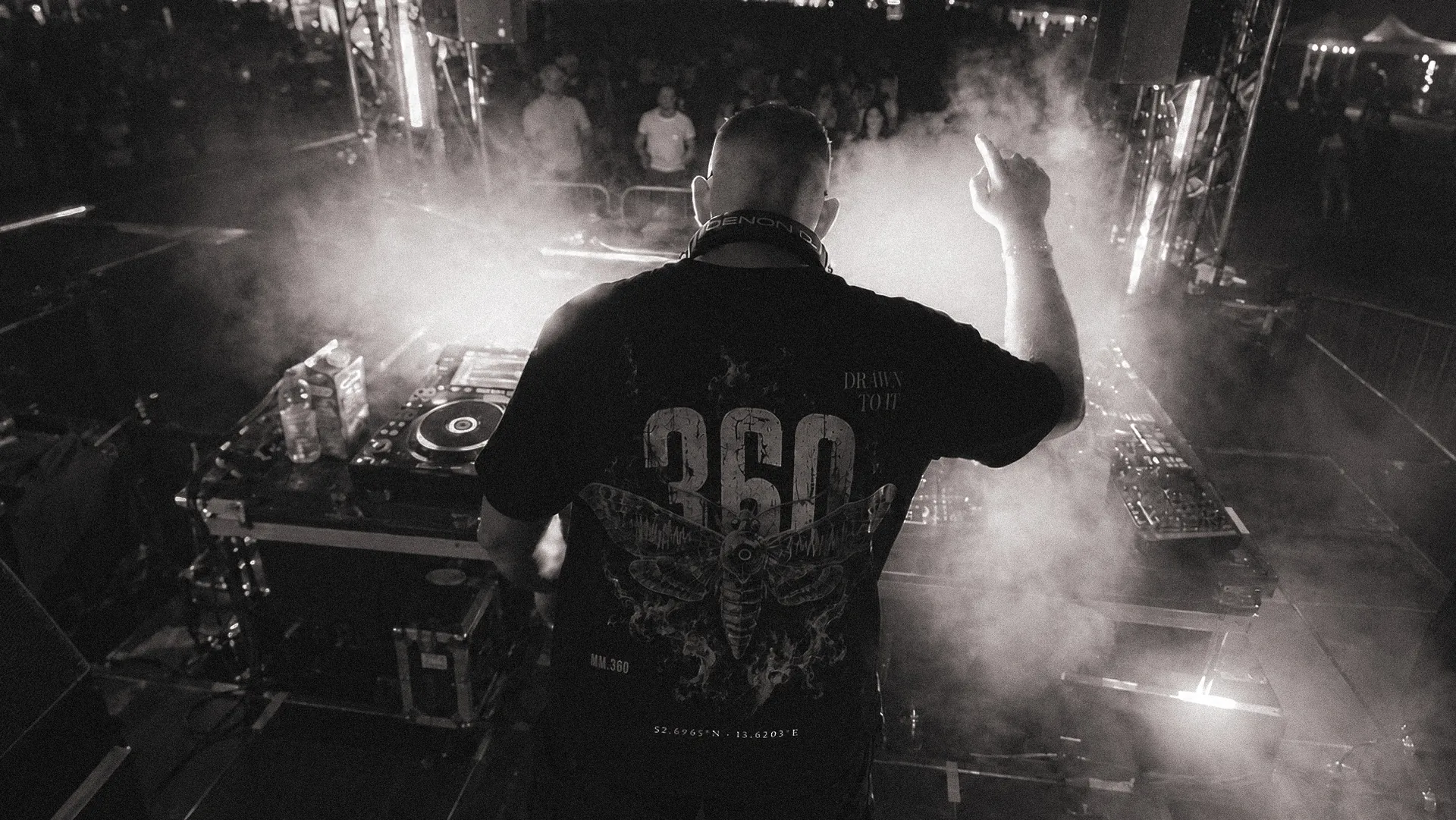 MM.360-Shirt am DJ-Pult, dahinter die Crowd im Licht